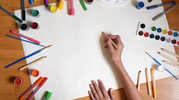 Klein meisje tekenen in papier op de vloer binnenshuis, bovenaanzicht van kind op de vloer - Video