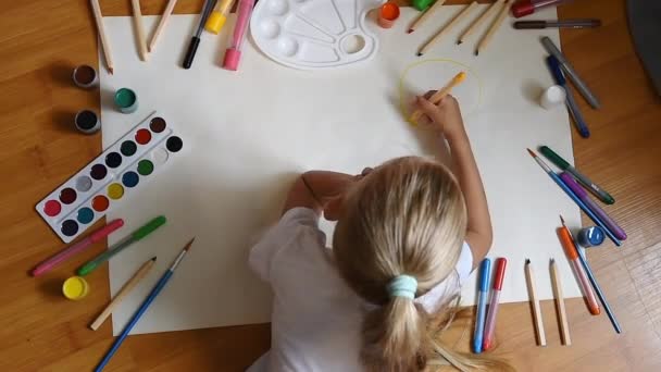 Маленька дівчинка малює в папері на підлозі в приміщенні, вид зверху дитини на підлогу
 - Кадри, відео