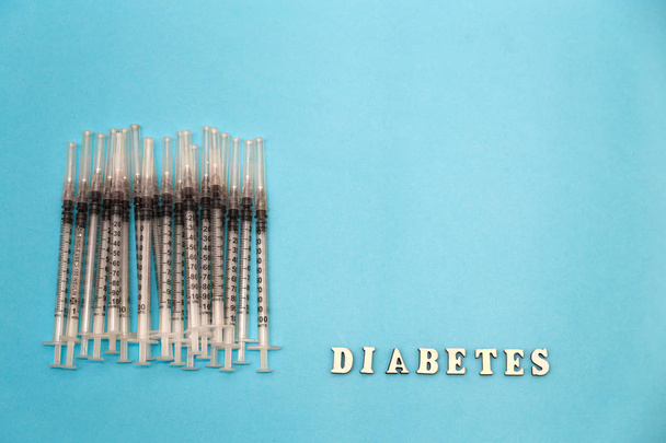A palavra diabetes com seringa de insulina, sobre um fundo azul
 - Foto, Imagem