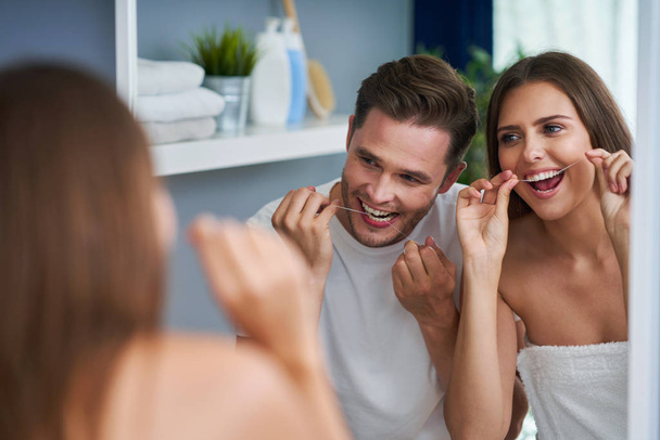 Портрет счастливой молодой пары с зубной нитью в ванной комнате
 - Фото, изображение