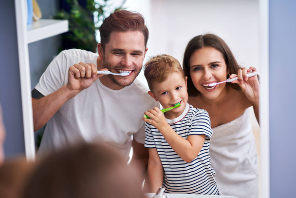 Портрет счастливой семьи, чистящей зубы в ванной
 - Фото, изображение