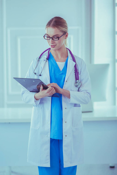 Smiling female doctor with a folder in uniform standing - Foto, Imagem