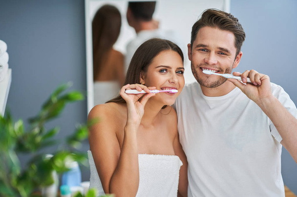 Retrato de feliz casal jovem escovando dentes no banheiro
 - Foto, Imagem
