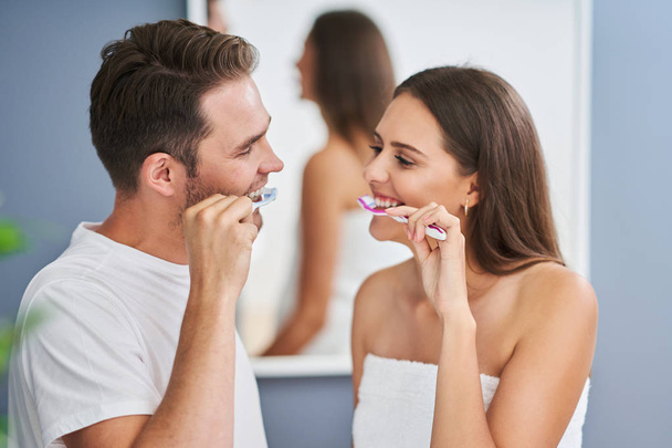 Portrait of happy young couple brushing teeth in the bathroom - Foto, Imagen