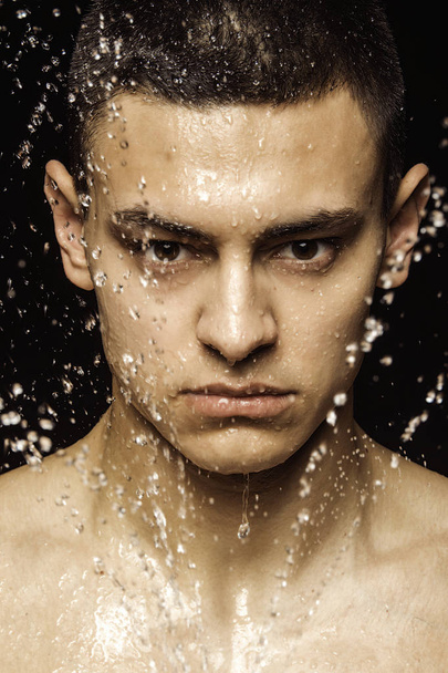 Handsome sport sexy stripped guy portrait with water drops in casual wear and underwear and towelon isolated black background - Photo, image
