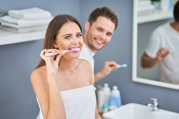 Portrait of happy young couple brushing teeth in the bathroom - Foto, imagen