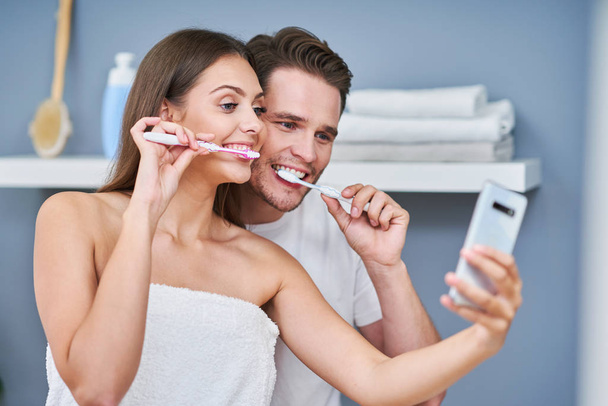 Portret van gelukkig jong stel tanden poetsen in de badkamer - Foto, afbeelding