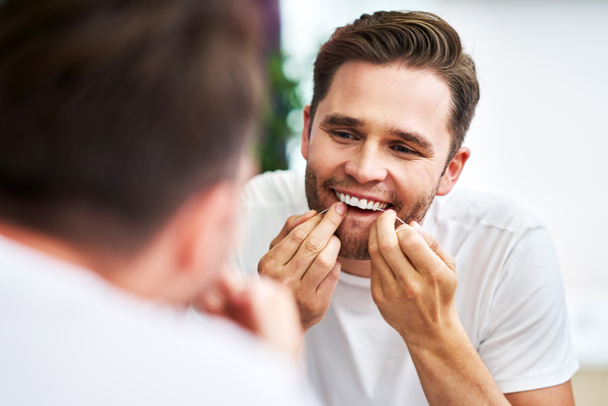 Erwachsener Mann Zahnseide Zähne im Badezimmer - Foto, Bild