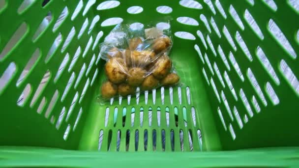 Close-up of supermarket trolley, woman puts vegetables and fruits to basket - Footage, Video