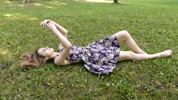 Dziewczyna z telefonem na trawie - Materiał filmowy, wideo