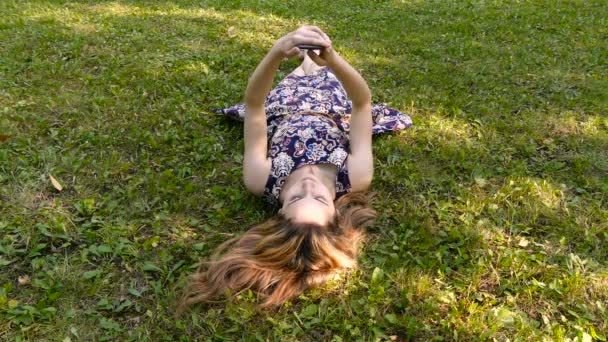 Dziewczyna z telefonem na trawie - Materiał filmowy, wideo