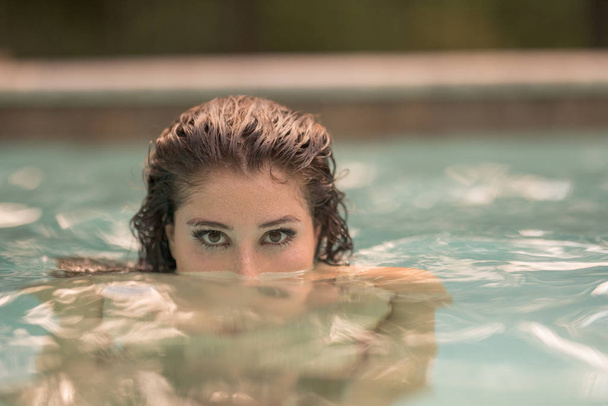 Attractive young woman sticking her head out of the water - Photo, image
