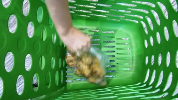 Κοντινό φύλλο θηλυκό χέρι βάζει τα λαχανικά και τα φρούτα σε καροτσάκι σούπερ μάρκετ - Πλάνα, βίντεο