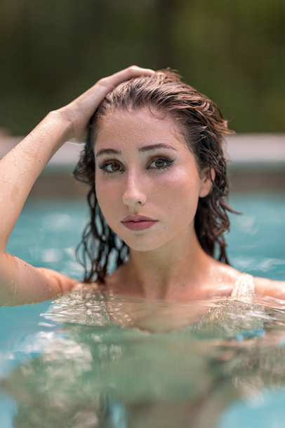 Bikini model posing in a pool with hand on head - Foto, imagen