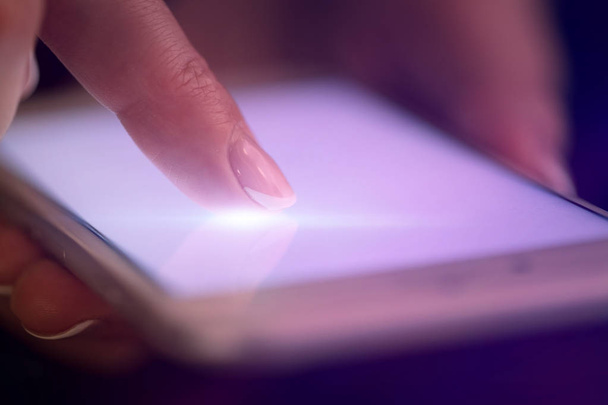 Finger touching phone with dark background - Photo, Image
