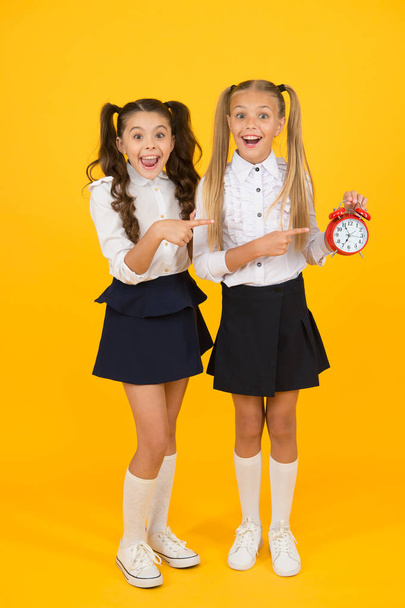 Time for lunch. School schedule. Schoolgirls and alarm clock. Children school pupils adorable formal uniform outfit. Kids hold alarm clock counting time. Time for break and relax. Alarm ringing - Fotoğraf, Görsel