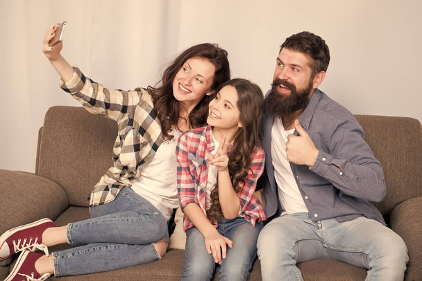 Selfie. Happy family at home. Modern smartphone. Little girl use smartphone with mother and father. bearded man and woman with child. Selfie mania. Family make selfie on smartphone. I love selfie - 写真・画像