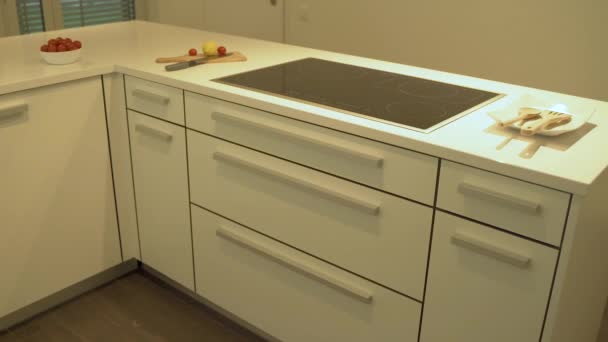 Progettazione di una moderna cucina bianca in armadi piatti bianchi con piano di lavoro in quarzo slow mo. Come concetto di design della cucina decorativo sotto le luci dell'armadio, cibo e piatti sono inclusi
. - Filmati, video