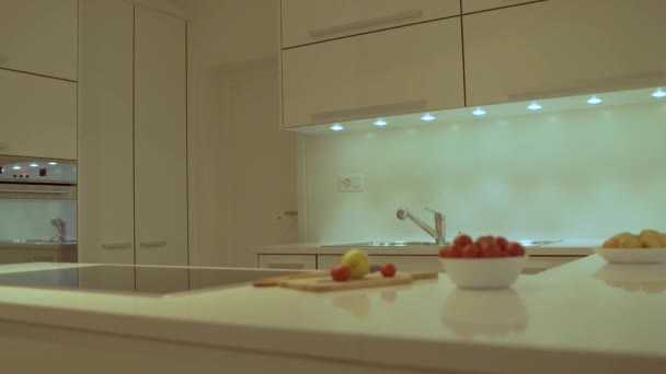 Estilo moderno de diseño de cocina con gabinete blanco plano, encimera de cocina blanca hecha de cuarzo con encimera de cocina eléctrica, gama y fregadero. Alimentos y platos decorativos se incluyen como concepto de diseño de cocina
. - Metraje, vídeo