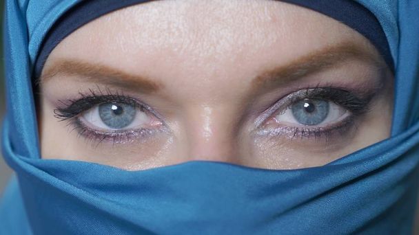 Close-up. mooie blauwe ogen van de Arabische jonge WoMA in traditionele islamitische doek niqab - Foto, afbeelding
