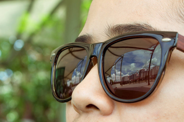 Gezicht vrouw dragen bruine zonnebrillen zijn op zoek naar de stad en - Foto, afbeelding