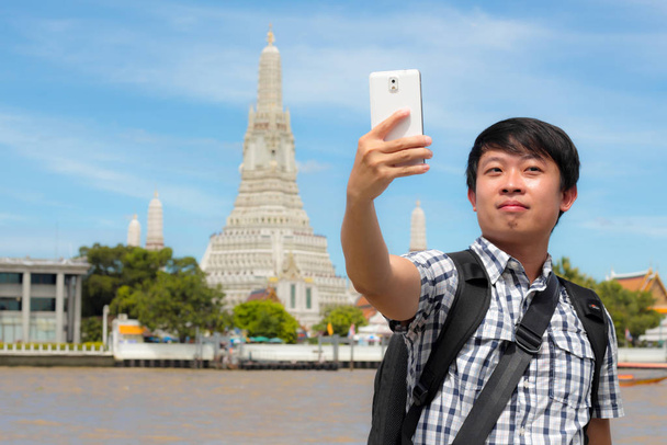 Turistas segurando um telefone celular para tirar fotos você mesmo sorrir
 - Foto, Imagem