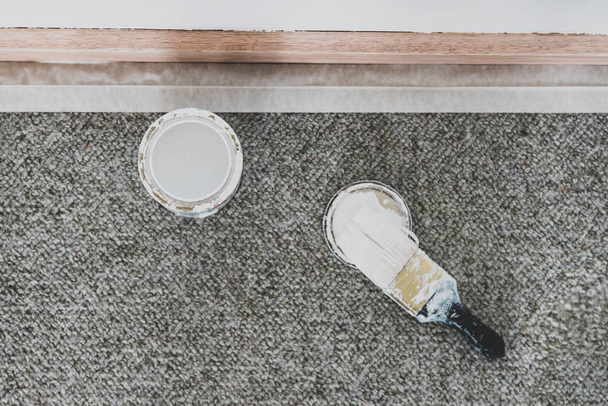 tin of white paint or primer with brush next to sanded wooden skirting boards - Foto, afbeelding