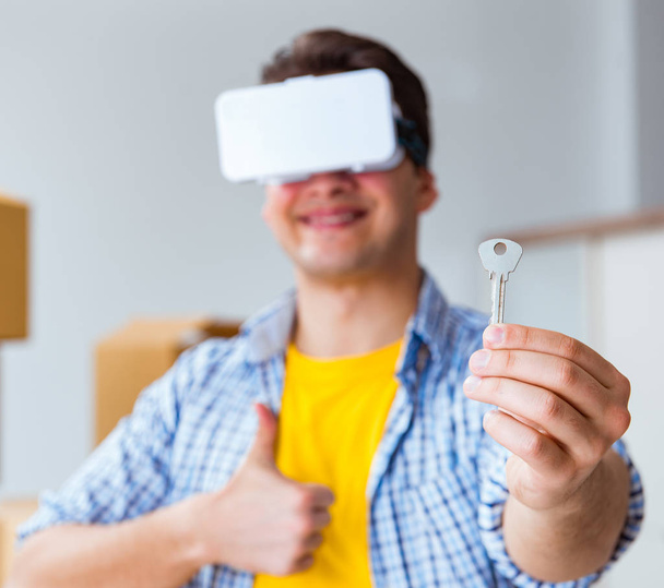 VR gözlüklü genç adam yeni daireye taşınıyor. - Fotoğraf, Görsel