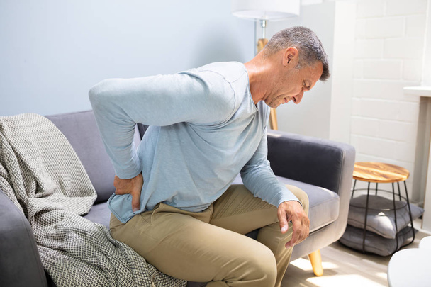 Man On Sofa Suffering From Backpain At Home - Foto, Imagem