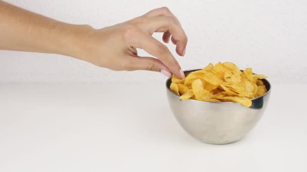 Female beautiful hands with take potato chips from a deep plate. Unhealthy food, fast food - Materiał filmowy, wideo