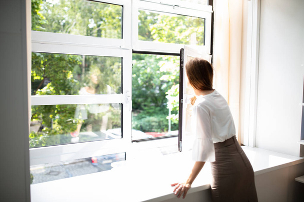 Side View Of A Businesswoman Looking Out Of A Window From An Office Building - Photo, Image