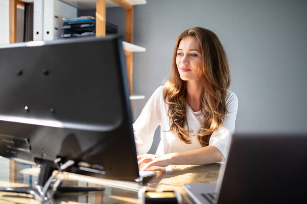 Smiling Young Businesswoman Working At Workplace In Front Of Computer - Foto, immagini