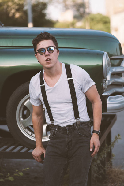Guy in a shirt with suspenders posing at the retro car - Zdjęcie, obraz