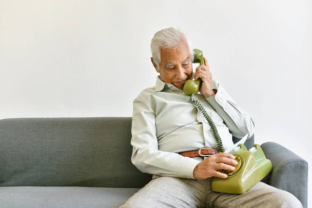 Азиатский старший старик телефонный звонок своим детям, одинокий дедушка разговаривает с семьей по старинному телефону дома, пожилой старый родитель был оставлен семьей
 - Фото, изображение