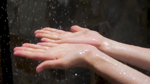 Wassertropfen tropfen auf Frauenhände. Zauberhaftes Spektakel. Wasser als Quelle des Lebens. Wassertropfen auf Frauenhände, - Filmmaterial, Video