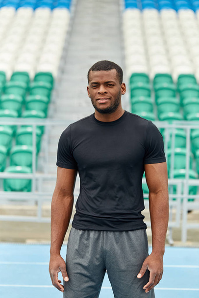 Close up photo of handsome well-built sportsman standing at the stadium - Fotó, kép