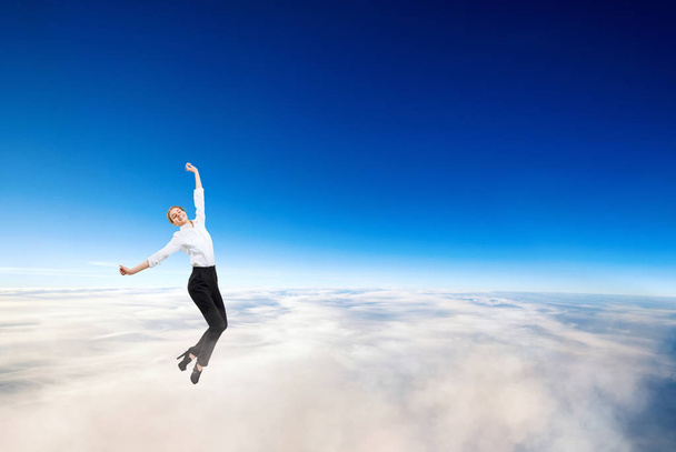 Businesswoman in formal wear flying in blue sky. - Foto, Imagen
