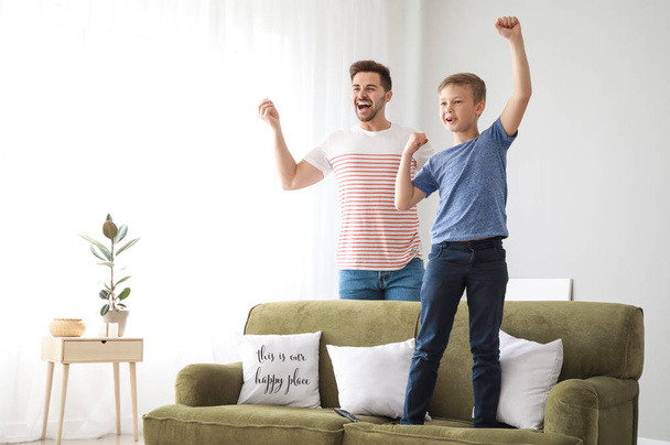 Padre con hijo viendo deportes en la televisión en casa
 - Foto, Imagen