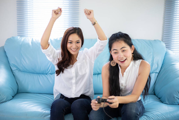 Kaksi naista pelaa kilpailukykyisiä videopelejä onnellisesti kotona
  - Valokuva, kuva