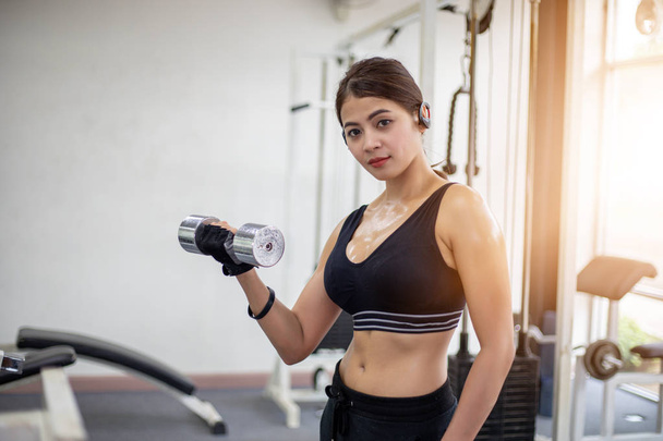 Mujer musculosa en forma ejercitando la construcción de músculos en el gimnasio. Fitness - concepto de estilo de vida saludable
. - Foto, Imagen