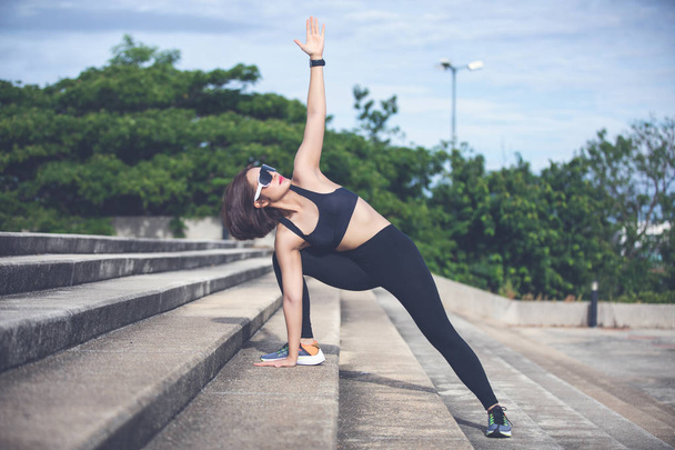 Atletische vrouw warming-up, uitoefening en stretching in Park voor joggen buitenshuis. - Foto, afbeelding