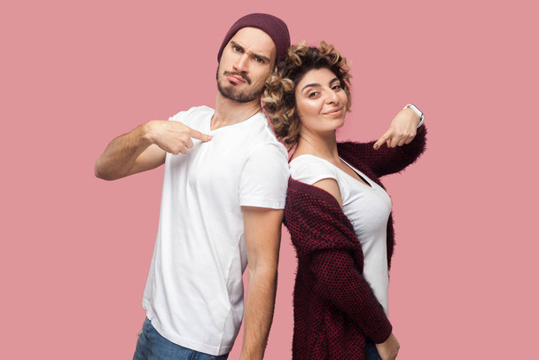 satisfied successful couple of friends in casual style standing back to back and pointing themself and looking at camera with proud faces on pink background - Fotoğraf, Görsel