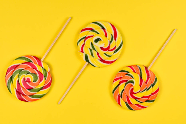 Colorful candy on a yellow  background. Lollipop. Top view. Copy - Foto, afbeelding