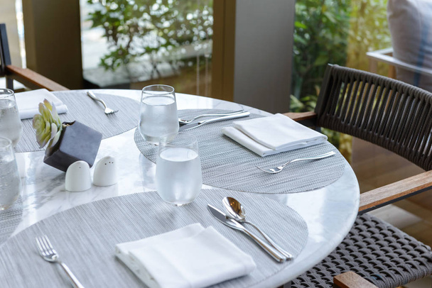 Nastavení tabulky v restauraci. Zdobený elegantní stolek, brýle, ubrousek, nůž, vidličku a lžíce - Fotografie, Obrázek