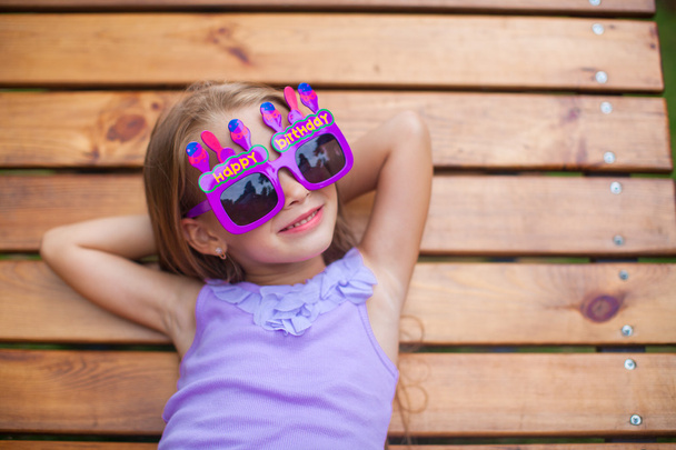 Adorable petite fille dans des lunettes de joyeux anniversaire amusez-vous en plein air
 - Photo, image