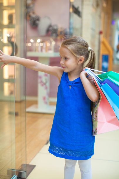 schattig meisje met pakketten in een groot winkelcentrum - Foto, afbeelding