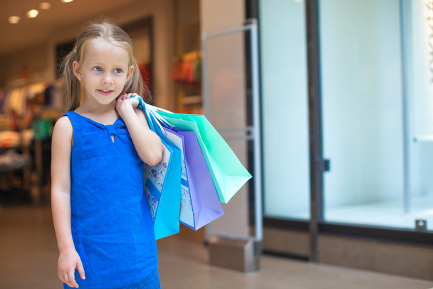 Portrait of little fashion girl holding shopping bags at the mall - Foto, imagen