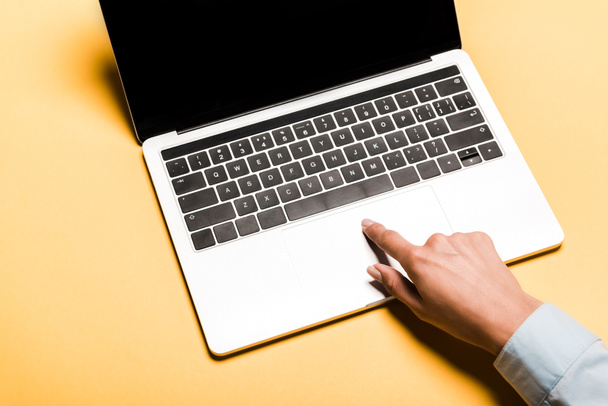cropped view of woman using laptop with blank screen on orange - Photo, Image