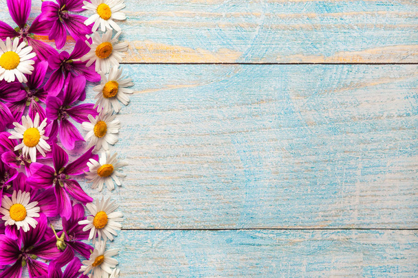 Садові фіолетові та білі квіти над синім старим дерев'яним столом з місцем для тексту
. - Фото, зображення