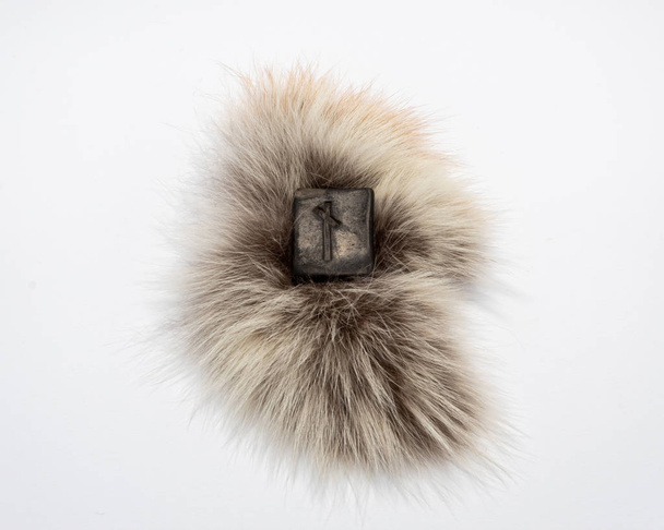 Norse rune Nautiz (Naud), isolated on fur and white  background.  Obstacles, the necessary awareness of difficulties and opportunities to overcome them. Strong bond, obligations. - Photo, Image
